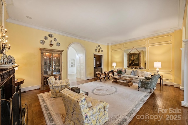 living room featuring baseboards, a fireplace, arched walkways, hardwood / wood-style flooring, and crown molding