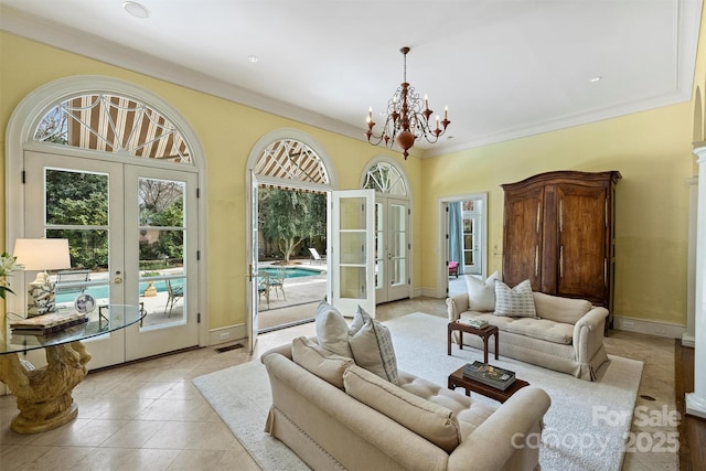 living area featuring a notable chandelier, french doors, light tile patterned flooring, crown molding, and baseboards