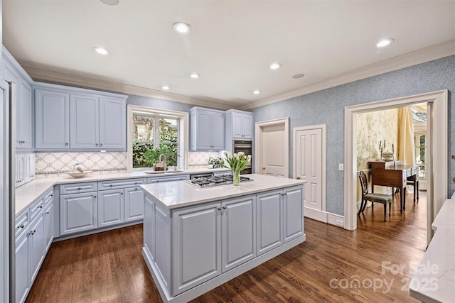 kitchen featuring a center island, dark wood-type flooring, light countertops, appliances with stainless steel finishes, and a sink