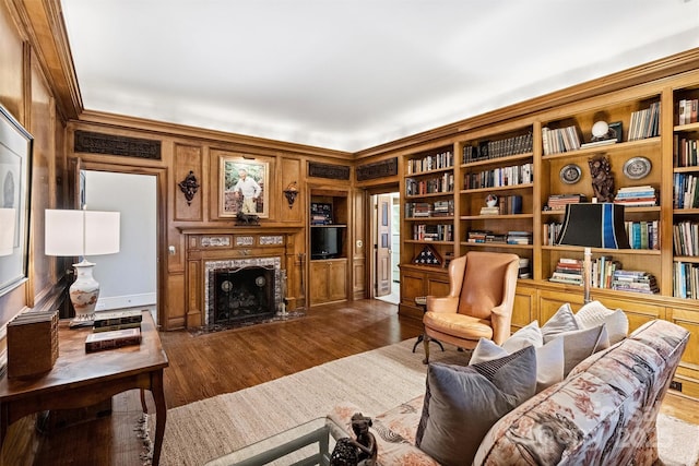 living room featuring a high end fireplace, built in features, and dark wood finished floors