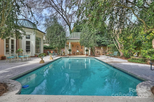 outdoor pool with an outbuilding and a patio area