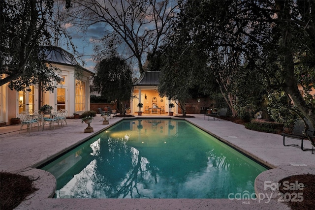 pool with a patio, an outdoor structure, and an exterior structure