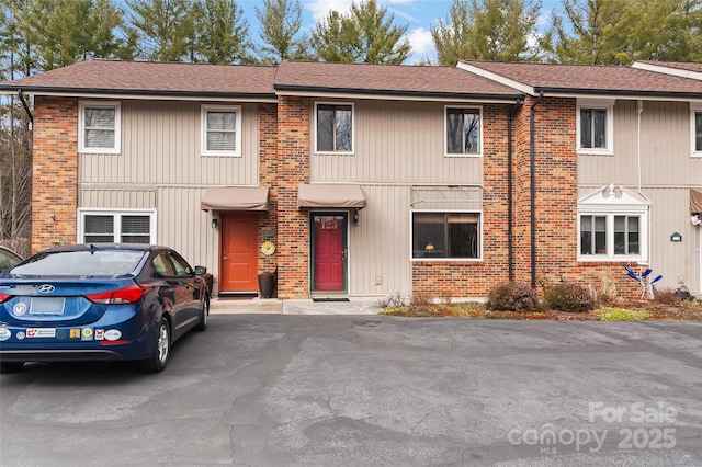 multi unit property featuring roof with shingles and brick siding