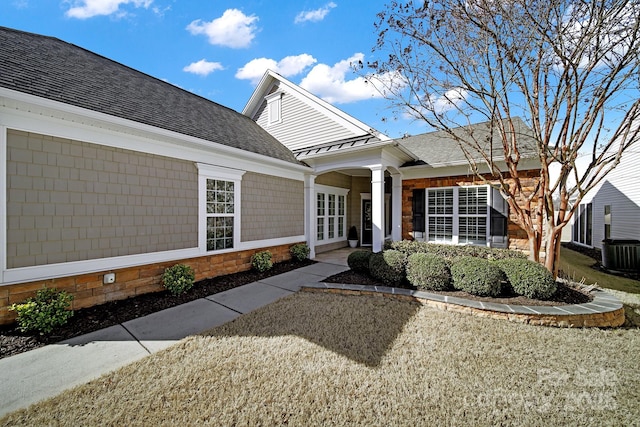 view of exterior entry with french doors, a shingled roof, a standing seam roof, metal roof, and cooling unit