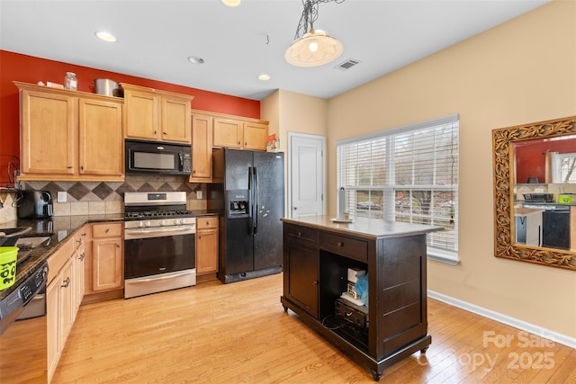 kitchen with visible vents, black appliances, light wood-style floors, decorative backsplash, and hanging light fixtures