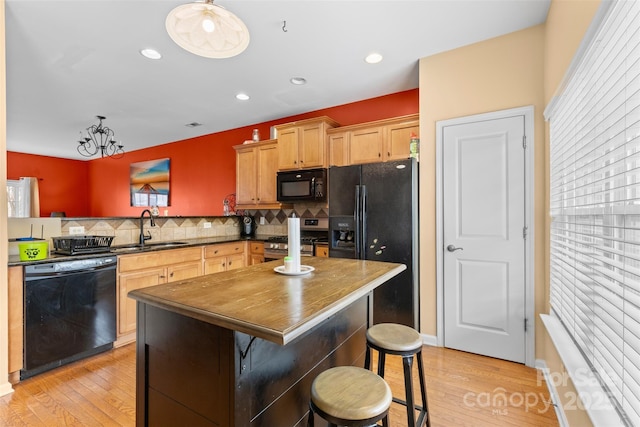 kitchen featuring backsplash, black appliances, light wood-type flooring, and a sink