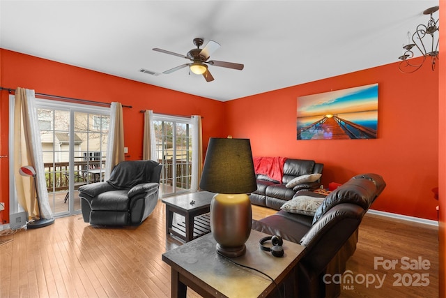 living room with hardwood / wood-style floors, baseboards, visible vents, and ceiling fan