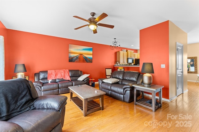 living room featuring light wood-type flooring, baseboards, and a ceiling fan