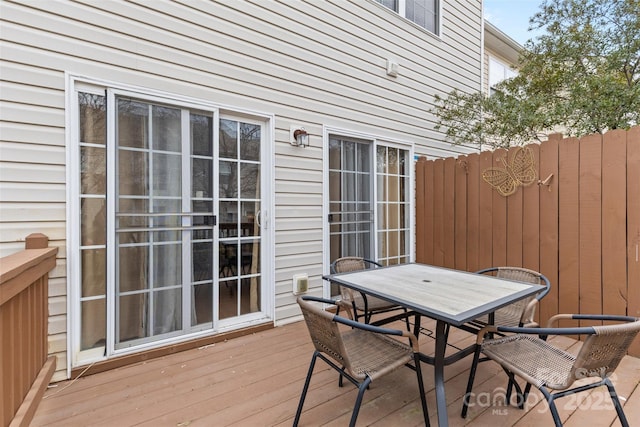 wooden terrace with outdoor dining space and fence