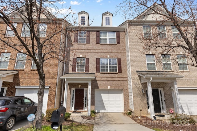 multi unit property featuring an attached garage, brick siding, and driveway