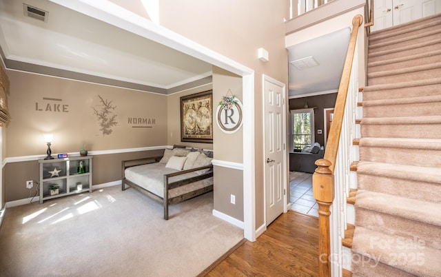 living area with visible vents, carpet, crown molding, baseboards, and stairs