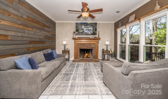 living area with wooden walls, a ceiling fan, visible vents, a fireplace, and crown molding