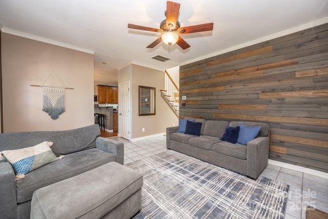 living area featuring visible vents, ornamental molding, stairway, wooden walls, and light tile patterned floors