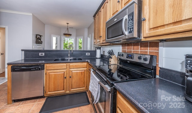 kitchen featuring tasteful backsplash, dark countertops, a peninsula, stainless steel appliances, and a sink