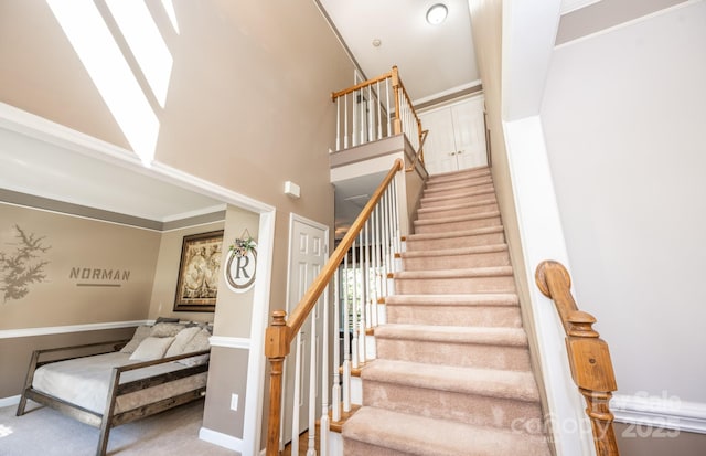 staircase with crown molding, a towering ceiling, and carpet floors