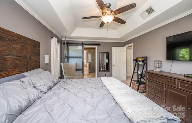 bedroom with a barn door, crown molding, visible vents, and a raised ceiling