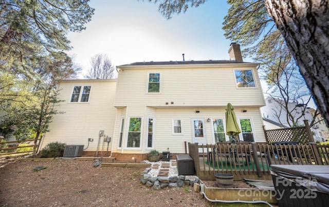 back of house with central air condition unit, a deck, and a chimney