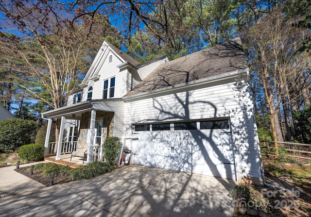 view of front of property featuring a porch, driveway, a garage, and fence