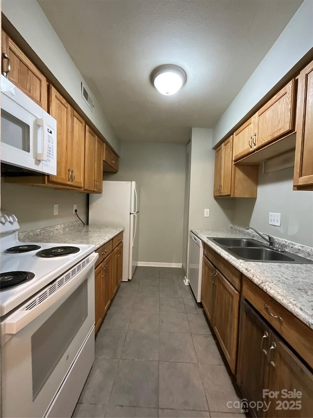 kitchen featuring white appliances, a sink, visible vents, light countertops, and tile patterned floors