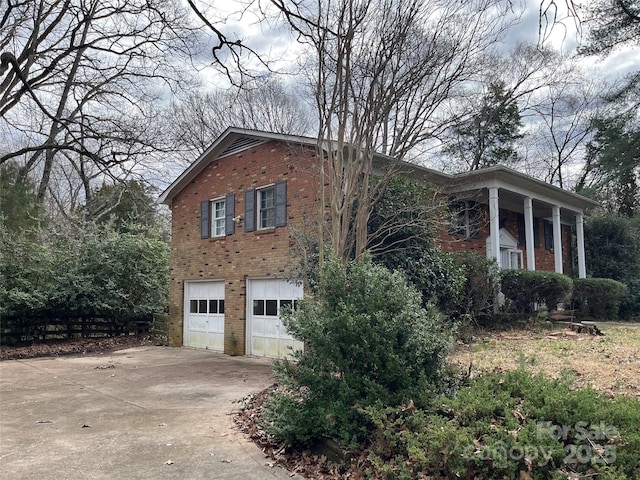 view of side of property with a garage, brick siding, and concrete driveway