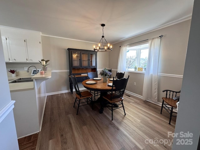 dining area with crown molding, a notable chandelier, wood finished floors, and baseboards