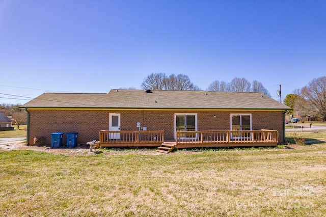 rear view of property with a yard, brick siding, and a deck