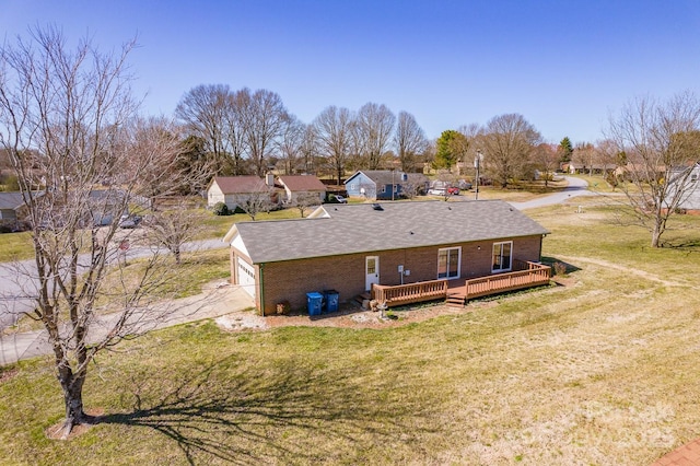 rear view of property with brick siding, a lawn, and a deck