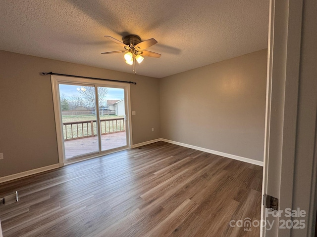 spare room featuring a ceiling fan, dark wood-style floors, and baseboards