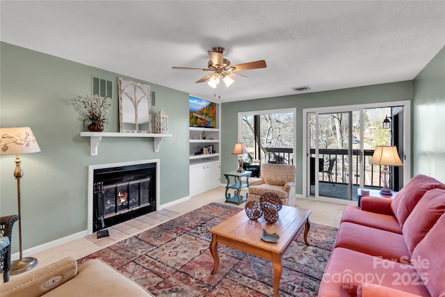 carpeted living area with visible vents, a fireplace with flush hearth, baseboards, and ceiling fan