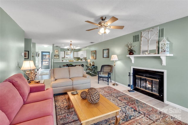 living room with visible vents, baseboards, a fireplace with flush hearth, tile patterned floors, and ceiling fan with notable chandelier