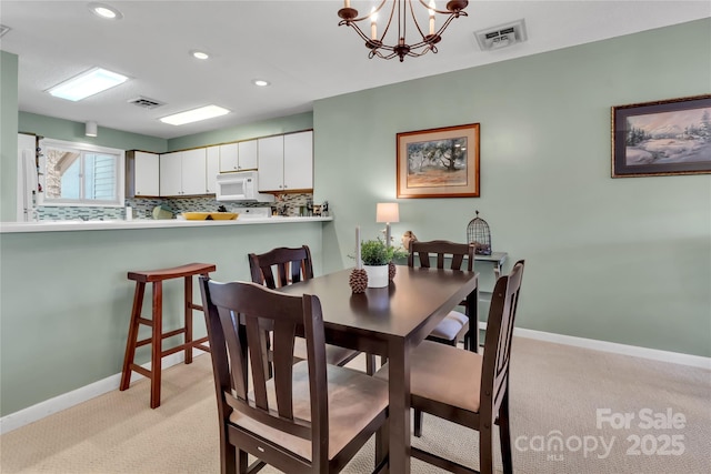 dining space featuring baseboards, light colored carpet, visible vents, and a chandelier