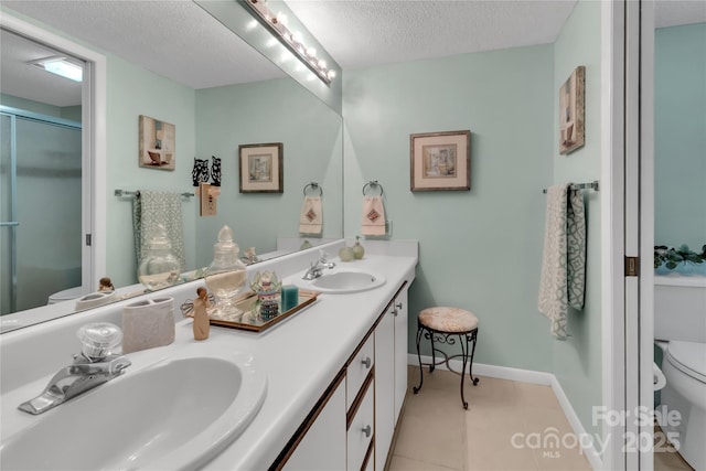 bathroom featuring double vanity, a sink, a shower stall, a textured ceiling, and toilet