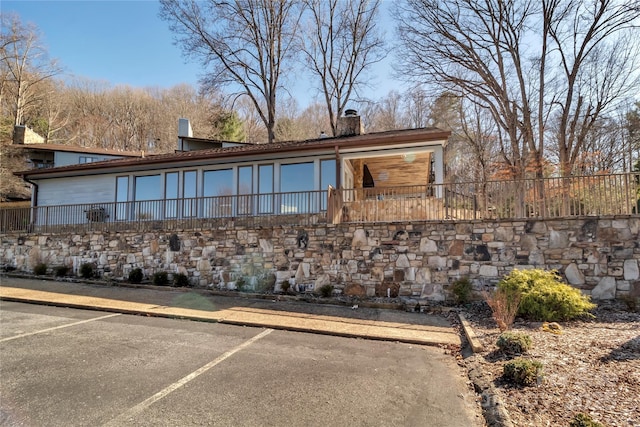 exterior space with uncovered parking, a chimney, and fence