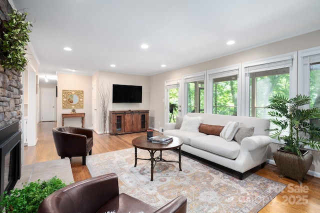 living room featuring recessed lighting, a fireplace, light wood-style floors, and baseboards