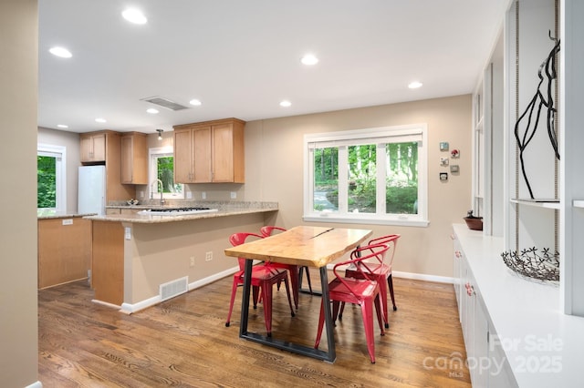 kitchen with a wealth of natural light, visible vents, freestanding refrigerator, and wood finished floors