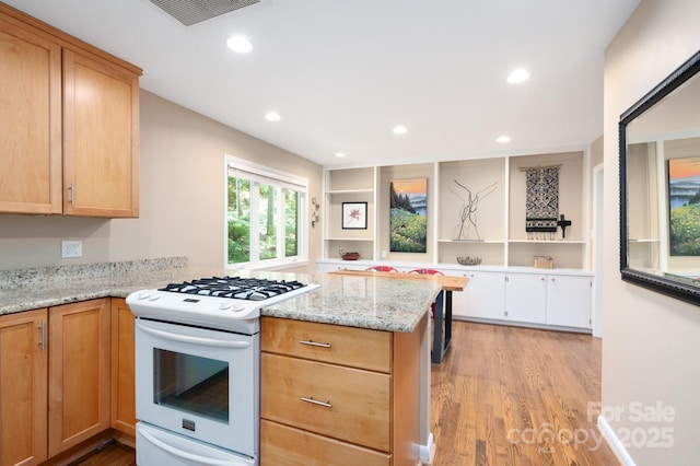 kitchen with light wood-type flooring, visible vents, gas range gas stove, recessed lighting, and a peninsula