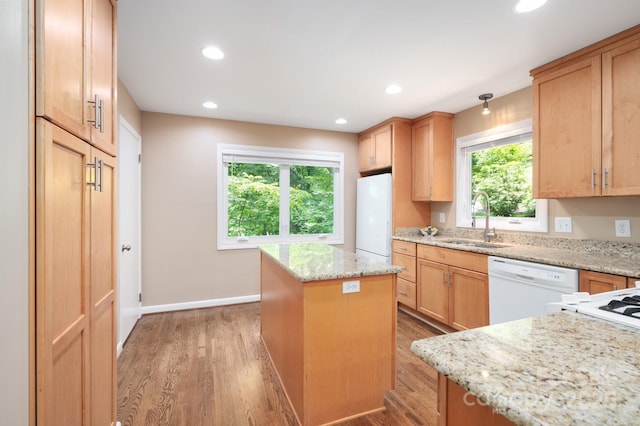 kitchen featuring light wood finished floors, white appliances, a kitchen island, and a sink