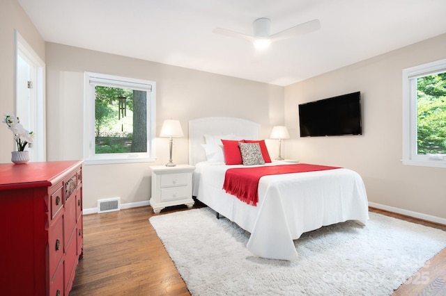 bedroom featuring visible vents, ceiling fan, baseboards, and wood finished floors