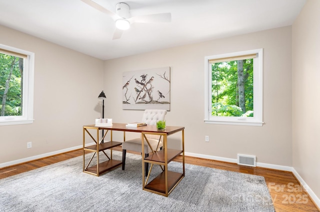 office area with visible vents, a healthy amount of sunlight, baseboards, and wood finished floors