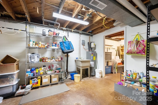 unfinished basement with visible vents, concrete block wall, and water heater