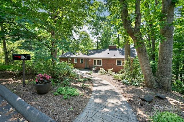 view of front of house with brick siding and a chimney