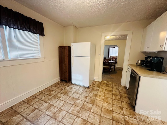 kitchen featuring freestanding refrigerator, light countertops, a textured ceiling, white cabinetry, and stainless steel dishwasher