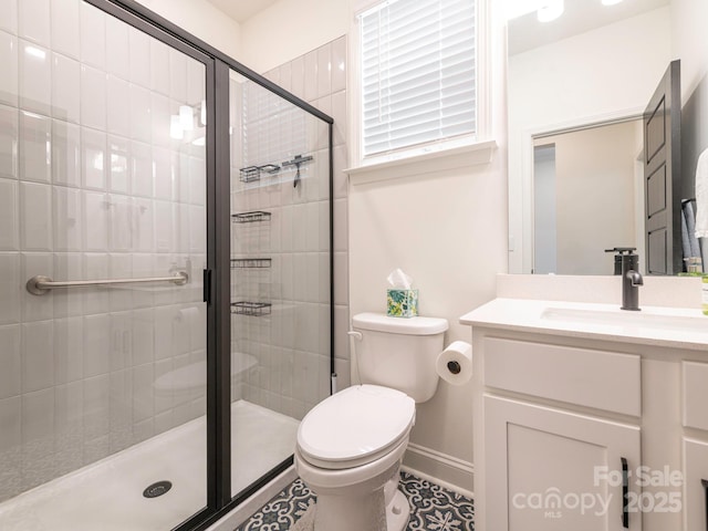 bathroom with baseboards, toilet, a stall shower, and vanity