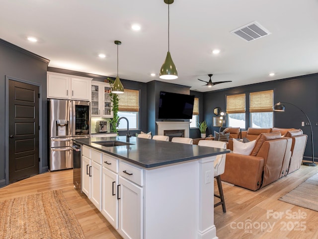 kitchen featuring visible vents, a fireplace, stainless steel appliances, a sink, and dark countertops