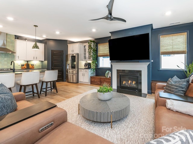 living area featuring visible vents, a fireplace with flush hearth, light wood-style flooring, recessed lighting, and ceiling fan