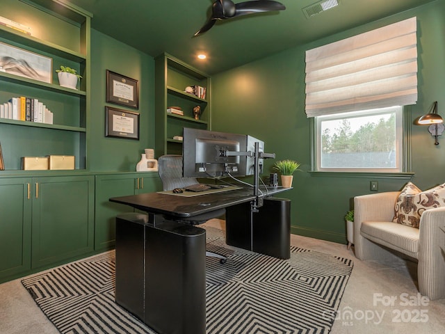 office space with visible vents, light colored carpet, and a ceiling fan