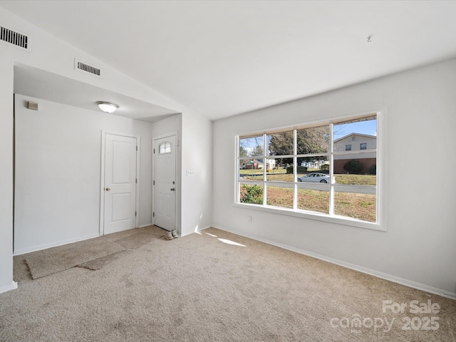 carpeted empty room featuring visible vents and baseboards