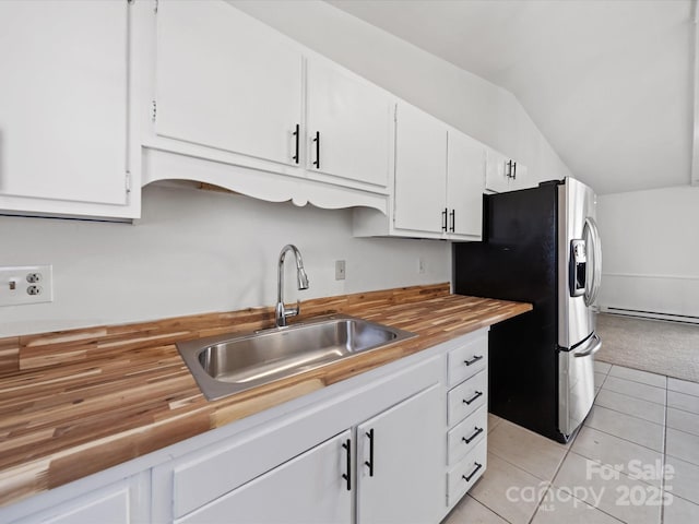 kitchen with lofted ceiling, a sink, wood counters, white cabinetry, and stainless steel fridge