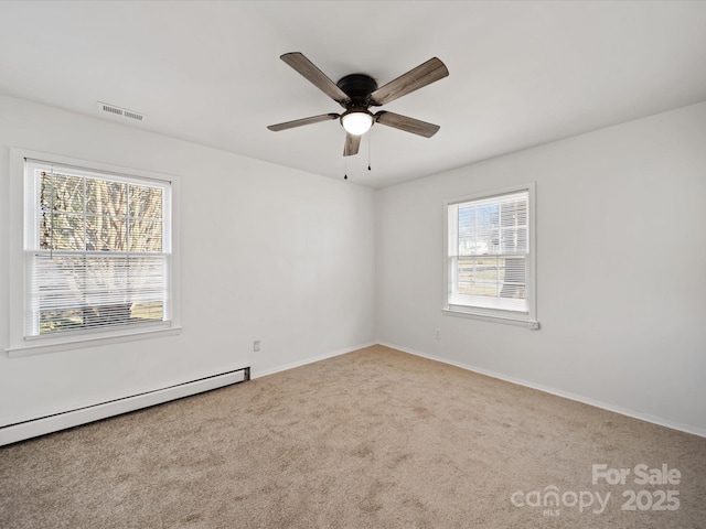 carpeted spare room featuring visible vents, a healthy amount of sunlight, a baseboard heating unit, and ceiling fan