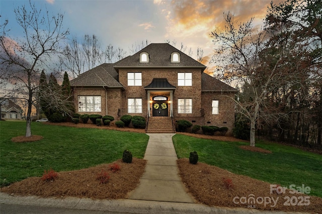 view of front of property featuring a yard, brick siding, and a shingled roof